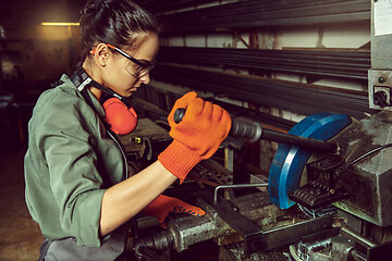 Image showing Busy and serious craftswoman grinding timbers with special machine.