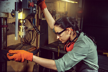 Image showing Busy and serious craftswoman grinding timbers with special machine.