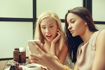 Image showing Two girl friends spend time together drinking coffee in the cafe, having breakfast and dessert.