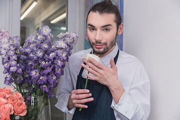 Image showing Small business. Male florist in flower shop. Floral design studio, making decorations and arrangements.