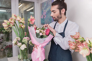 Image showing Small business. Male florist in flower shop. Floral design studio, making decorations and arrangements.