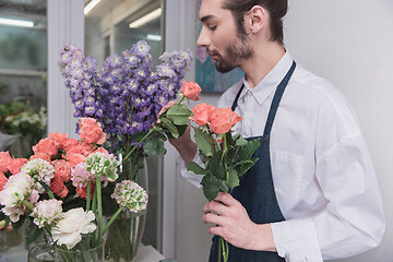 Image showing Small business. Male florist in flower shop. Floral design studio, making decorations and arrangements.