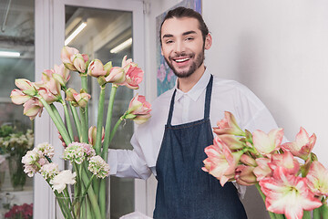 Image showing Small business. Male florist in flower shop. Floral design studio, making decorations and arrangements.