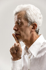 Image showing Serious frightened male keeps fore finger on lips