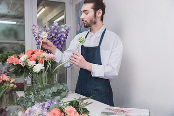 Image showing Small business. Male florist in flower shop. Floral design studio, making decorations and arrangements.