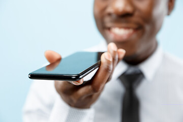 Image showing Indoor portrait of attractive young black man holding blank smartphone