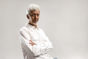 Image showing The serious businessman standing and looking at camera against gray background.