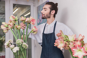 Image showing Small business. Male florist in flower shop. Floral design studio, making decorations and arrangements.