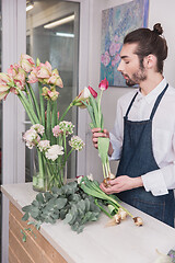 Image showing Small business. Male florist in flower shop. Floral design studio, making decorations and arrangements.