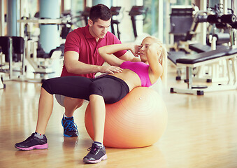 Image showing young sporty woman with trainer exercise in fitness gym