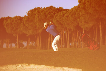 Image showing golfer hitting a sand bunker shot on sunset