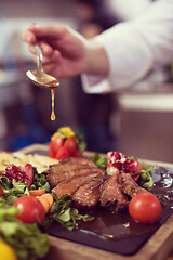 Image showing Chef hand finishing steak meat plate