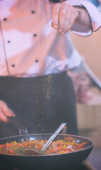 Image showing chef putting spices on vegetables in wok