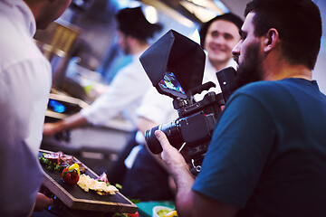 Image showing videographer recording while team cooks and chefs preparing meal