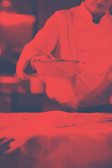 Image showing chef sprinkling flour over fresh pizza dough