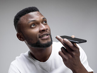 Image showing Indoor portrait of attractive young black man holding blank smartphone