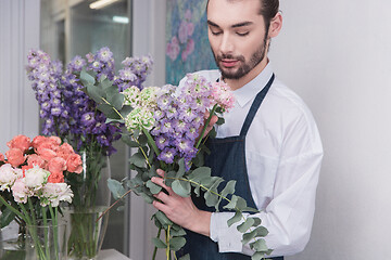 Image showing Small business. Male florist in flower shop. Floral design studio, making decorations and arrangements.