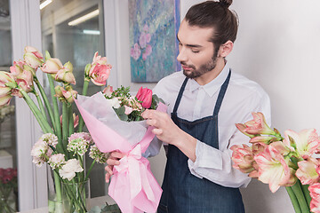 Image showing Small business. Male florist in flower shop. Floral design studio, making decorations and arrangements.