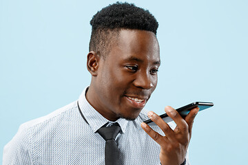 Image showing Indoor portrait of attractive young black man holding blank smartphone