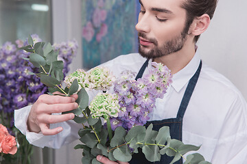 Image showing Small business. Male florist in flower shop. Floral design studio, making decorations and arrangements.