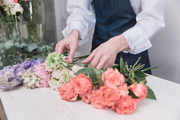 Image showing Small business. Male florist in flower shop. Floral design studio, making decorations and arrangements.