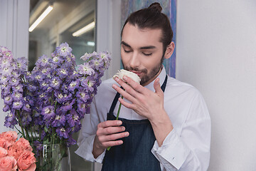 Image showing Small business. Male florist in flower shop. Floral design studio, making decorations and arrangements.