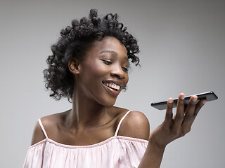 Image showing Indoor portrait of attractive young black woman holding blank smartphone