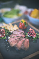 Image showing Juicy slices of grilled steak on wooden board