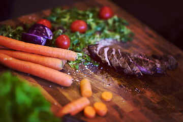 Image showing Juicy slices of grilled steak on wooden board