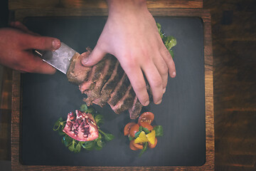 Image showing top view of Chef hands serving beef steak