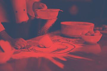 Image showing chef sprinkling flour over fresh pizza dough