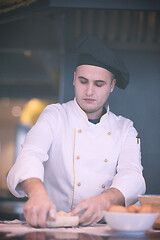 Image showing young chef preparing dough for pizza