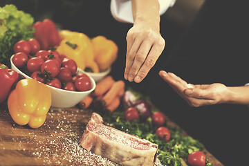 Image showing Chef putting salt on juicy slice of raw steak