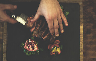 Image showing top view of Chef hands serving beef steak