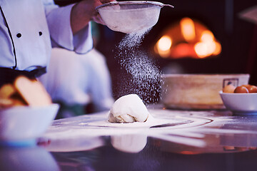 Image showing chef sprinkling flour over fresh pizza dough