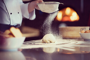 Image showing chef sprinkling flour over fresh pizza dough