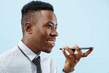 Image showing Indoor portrait of attractive young black man holding blank smartphone