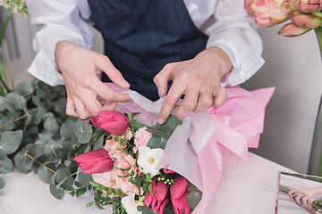 Image showing Small business. Male florist in flower shop. Floral design studio, making decorations and arrangements.