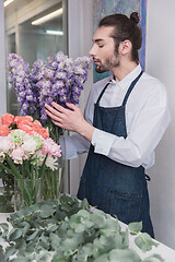 Image showing Small business. Male florist in flower shop. Floral design studio, making decorations and arrangements.