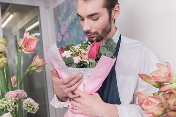 Image showing Small business. Male florist in flower shop. Floral design studio, making decorations and arrangements.