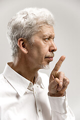 Image showing Serious frightened male keeps fore finger on lips