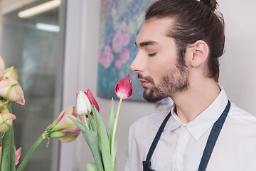 Image showing Small business. Male florist in flower shop. Floral design studio, making decorations and arrangements.