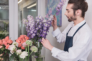 Image showing Small business. Male florist in flower shop. Floral design studio, making decorations and arrangements.