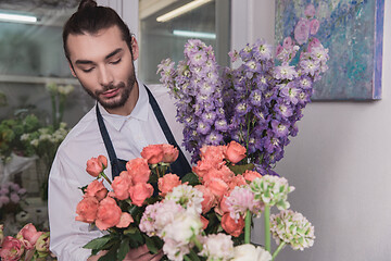 Image showing Small business. Male florist in flower shop. Floral design studio, making decorations and arrangements.