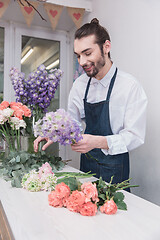 Image showing Small business. Male florist in flower shop. Floral design studio, making decorations and arrangements.