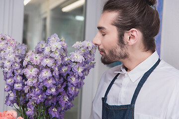 Image showing Small business. Male florist in flower shop. Floral design studio, making decorations and arrangements.