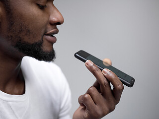 Image showing Indoor portrait of attractive young black man holding blank smartphone