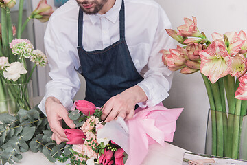 Image showing Small business. Male florist in flower shop. Floral design studio, making decorations and arrangements.