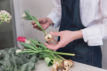 Image showing Small business. Male florist in flower shop. Floral design studio, making decorations and arrangements.