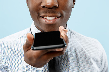 Image showing Indoor portrait of attractive young black man holding blank smartphone